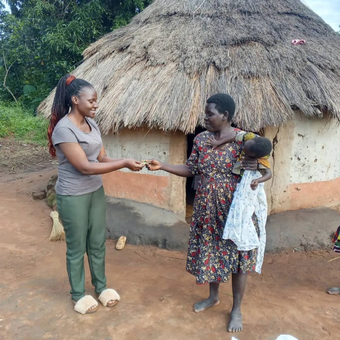 Team member offering practical support to a mother holding her baby outside her home