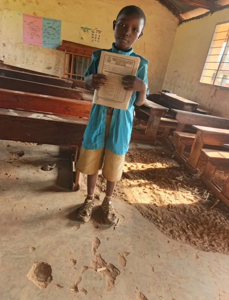 Student showing schoolwork inside a classroom in poor condition