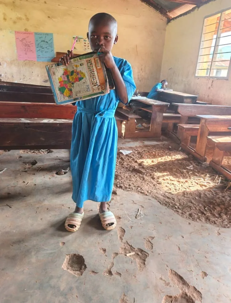 Schoolgirl holding learning material inside a damaged classroom
