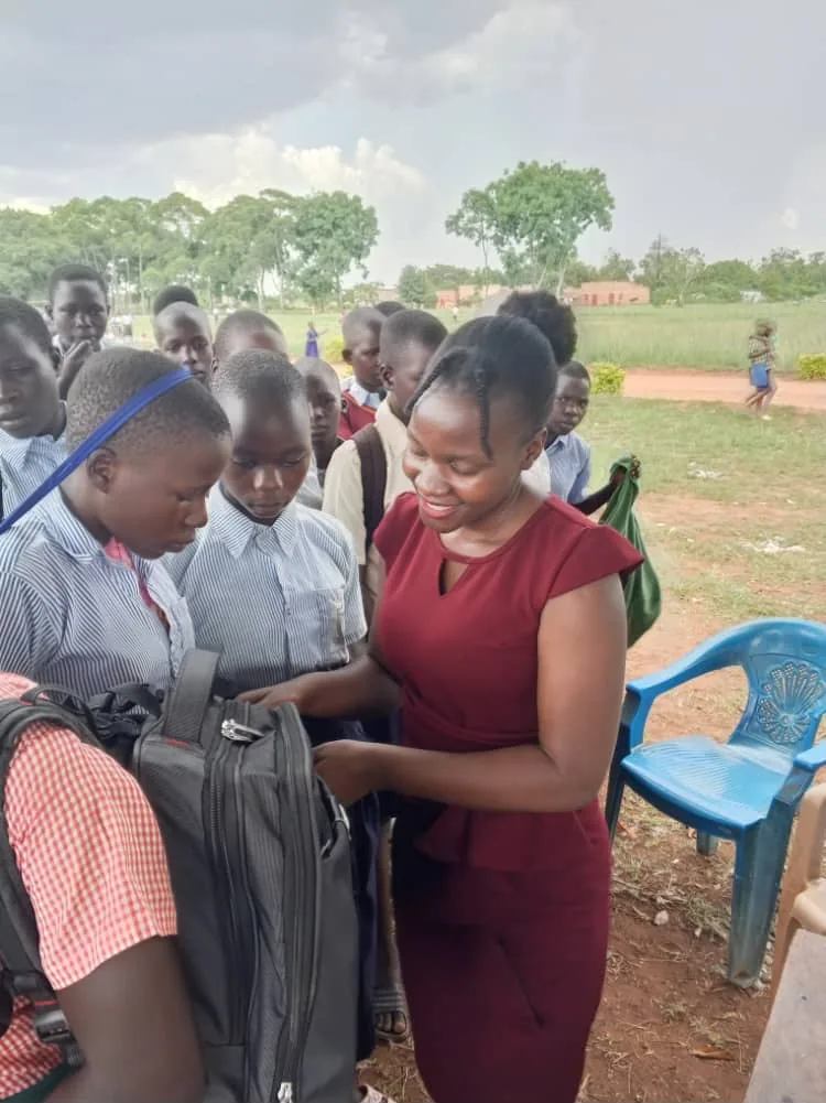 Team member handing school bags to pupils during a scholastic materials distribution