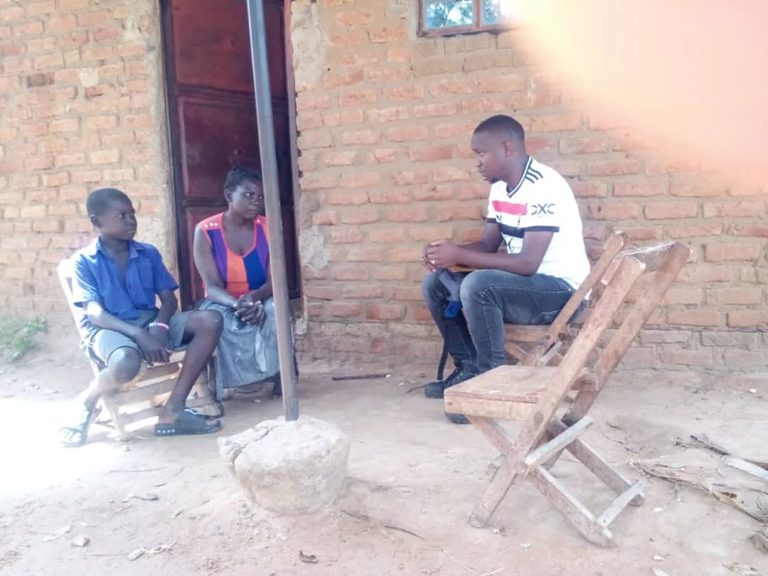 Team member speaking with a sponsored child and caregiver during a home visit