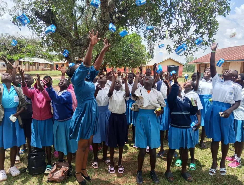 Schoolgirls celebrating outdoors after receiving sanitary kits