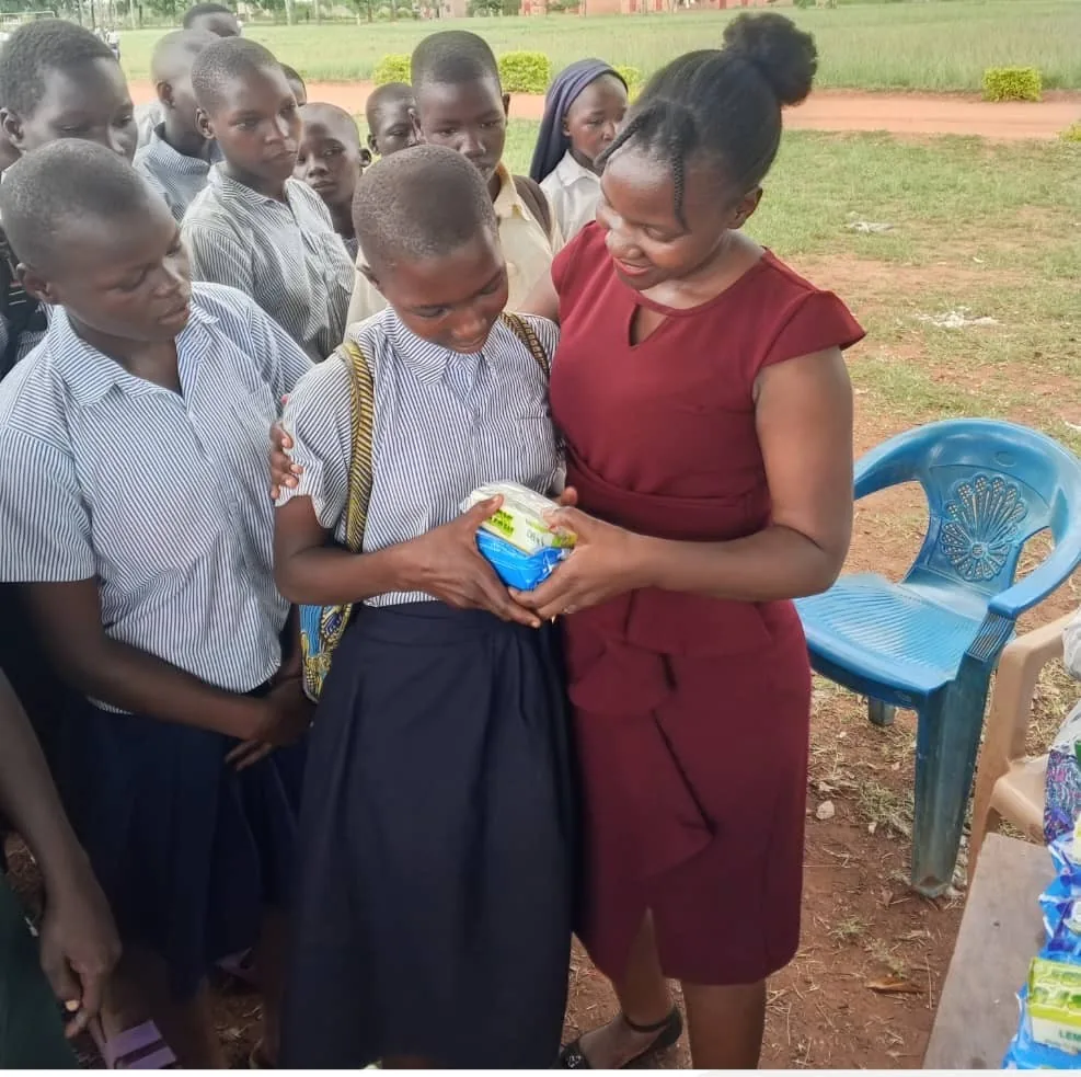 Team member giving sanitary pads and soap to a schoolgirl