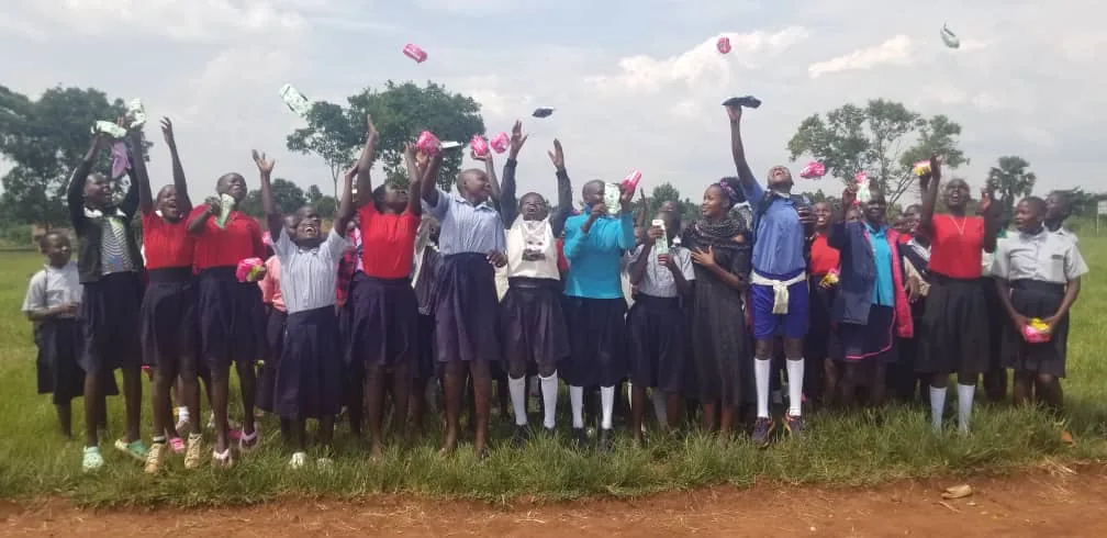 Large group of schoolgirls celebrating together after a sanitary kit distribution