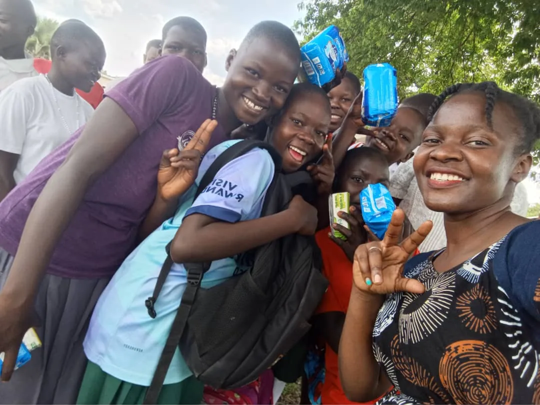 Schoolgirls smiling together while holding the sanitary kits they received