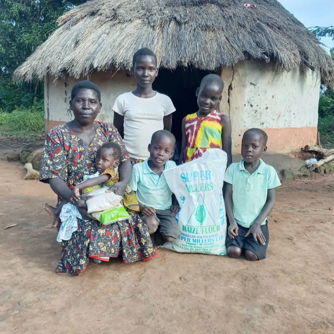 A family standing outside their home with a sack of maize flour received through nutrition support