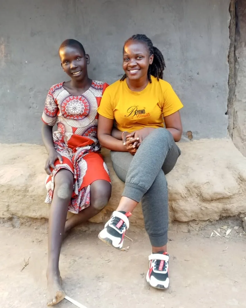 Mentor seated beside a young girl during a community visit
